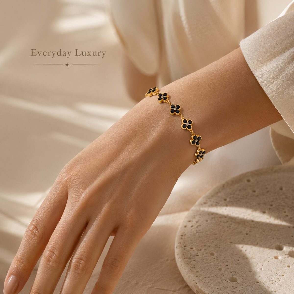 Elegant close up wearing image of a gold tone clover crystal bracelet on the wrist, styled with a refined neck and collarbone fashion look for a luxury jewelry store.
