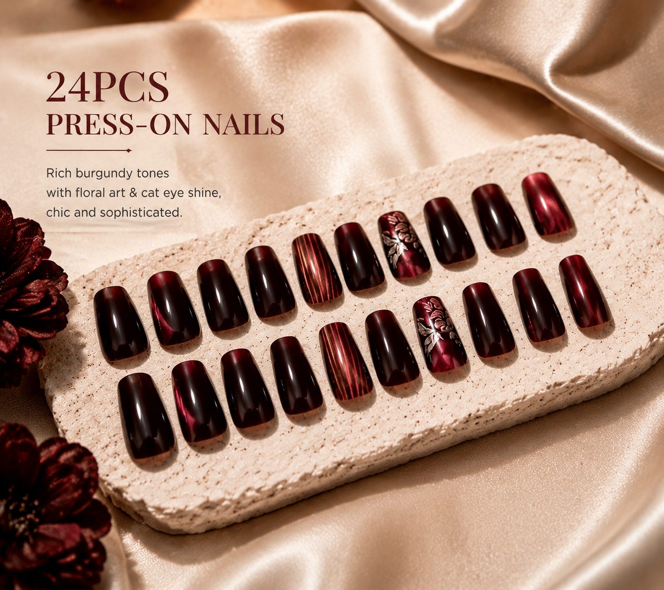 24-piece burgundy press-on nails displayed on a soft satin background, featuring rich red tones, floral details, and glossy shine.