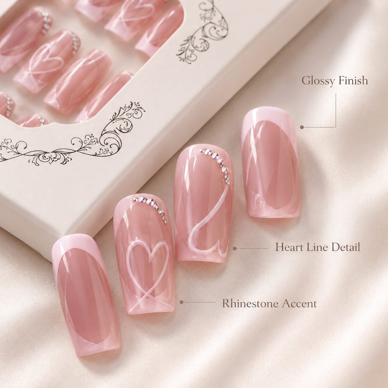 Close-up detail of glossy pink heart press-on nails with French tips, white line art, and rhinestone accents