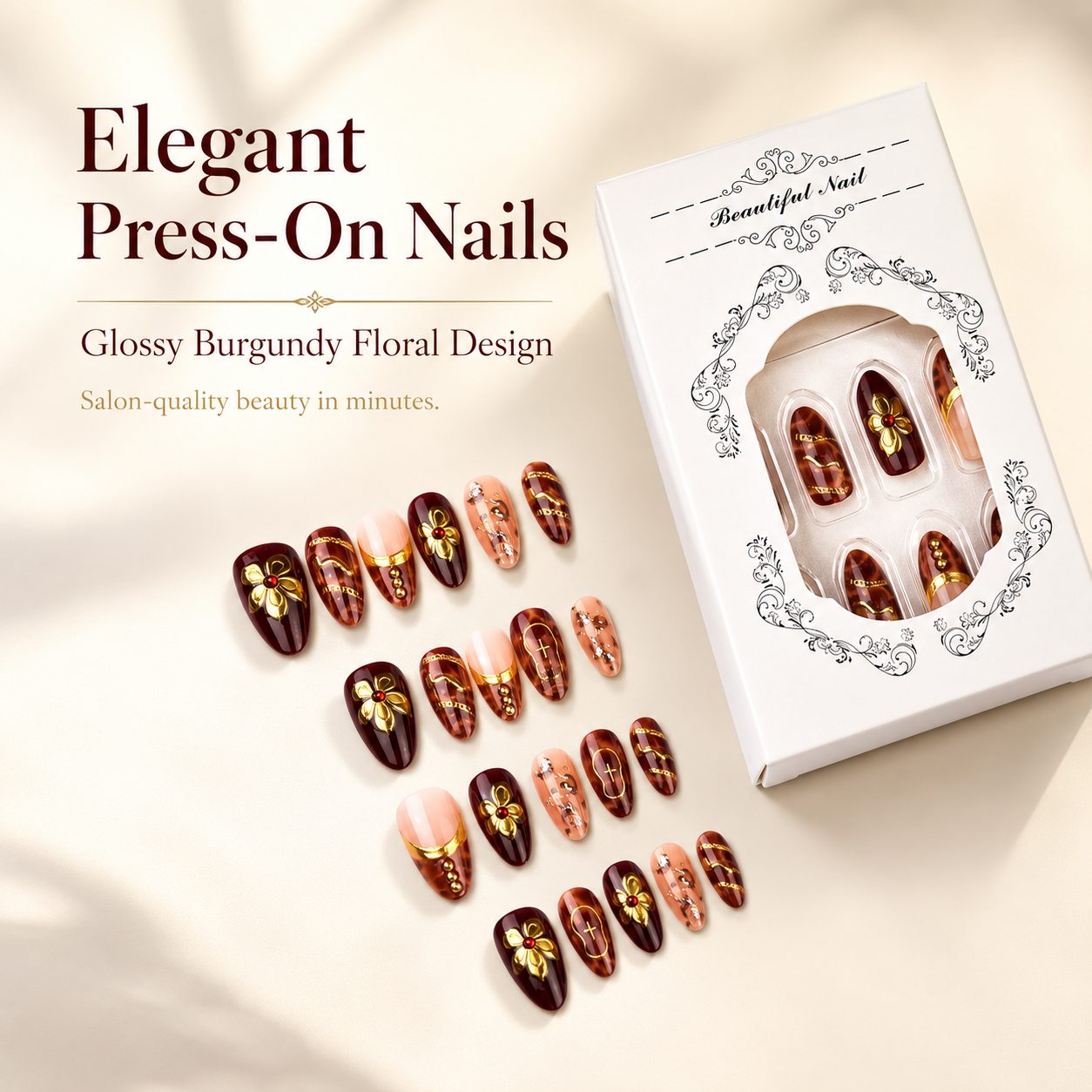 Elegant burgundy floral press-on nails with gold accents and white luxury packaging for independent beauty store