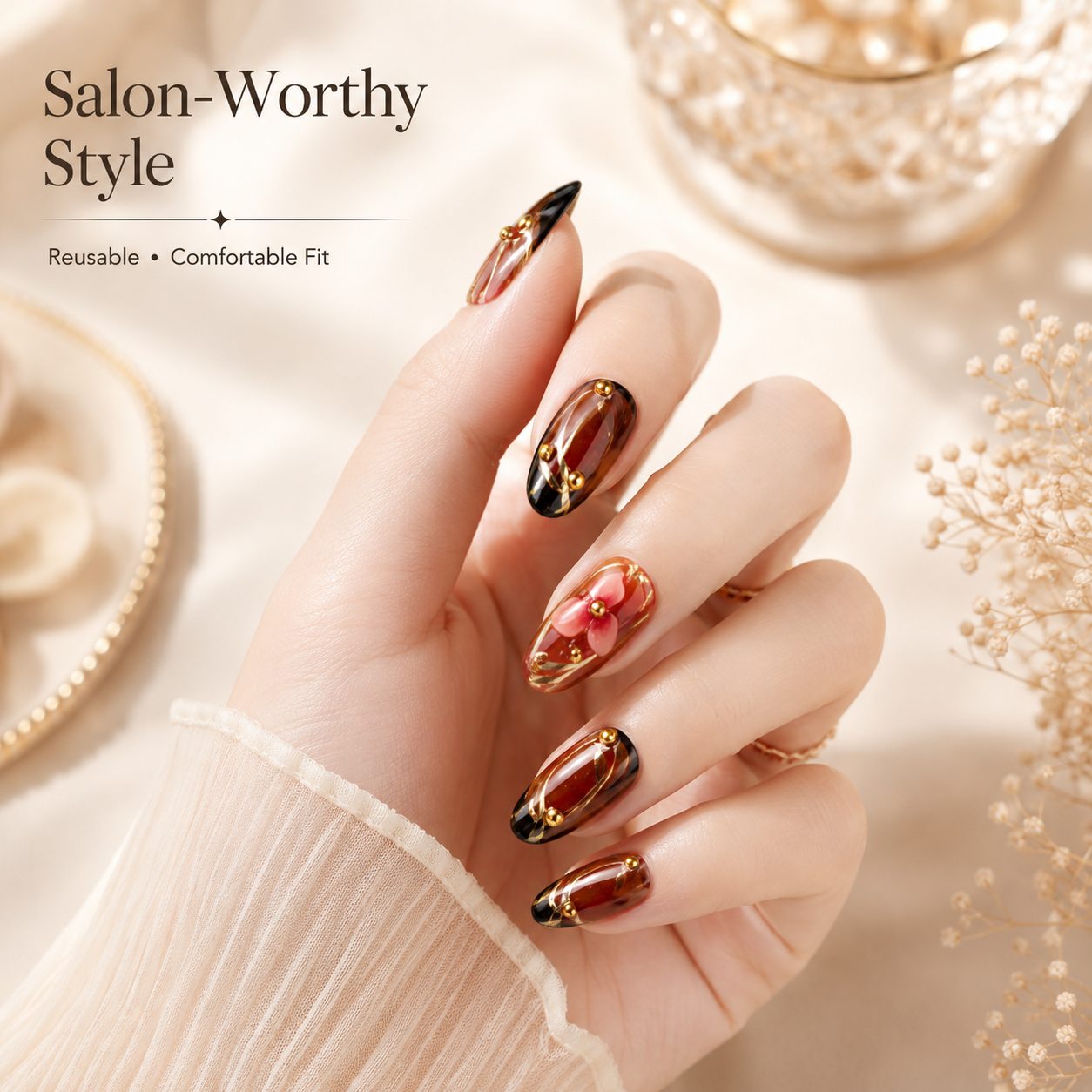 Hand model wearing brown floral press-on nails with glossy finish, gold accents, and elegant salon-style manicure look