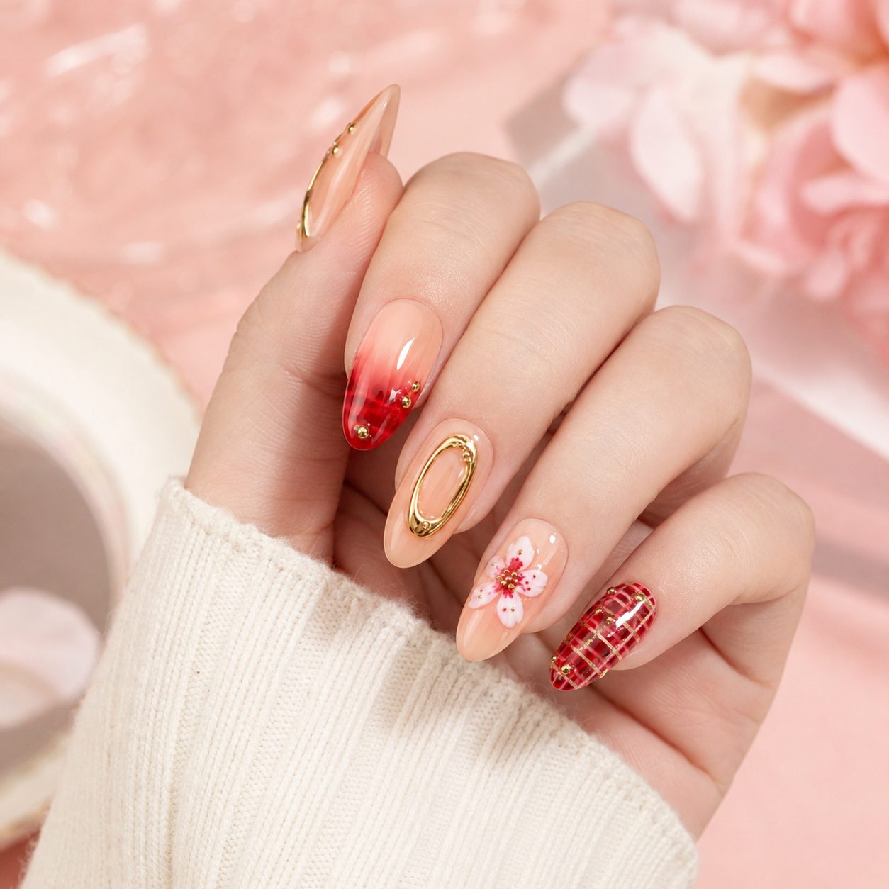 Fair skin hand wearing elegant floral gold press-on nails with red nude glossy manicure design