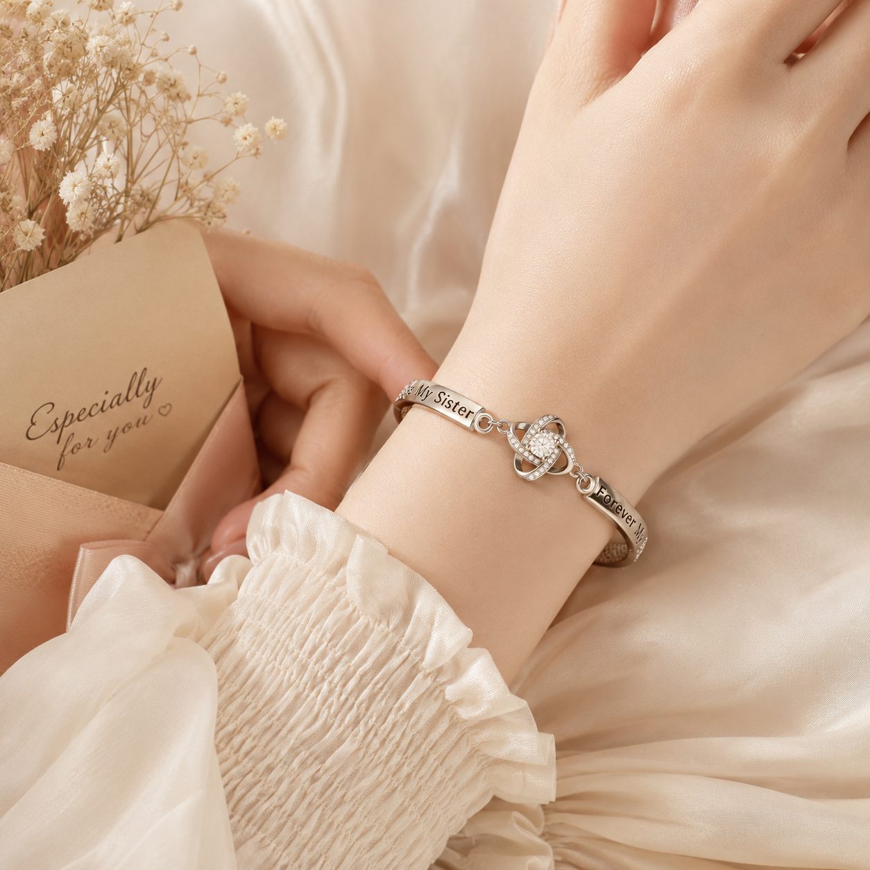 Light skin tone wrist wearing silver To My Sister bracelet with sparkling CZ charm on soft satin background